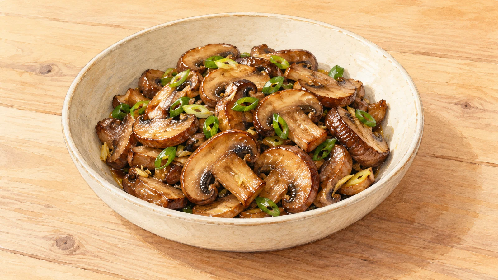 Watercolor illustration of browned mushroom slices coated in a light soy glaze with ginger and green scallion rings in a shallow bowl