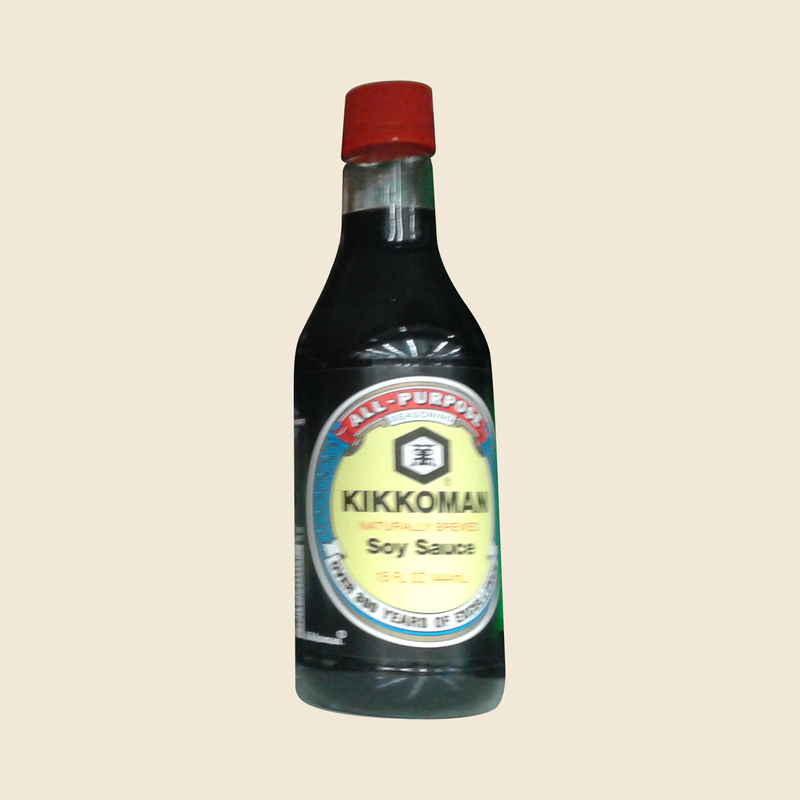 Complete red-capped Kikkoman Soy Sauce 15 fl oz bottle on a beige background